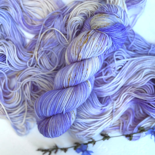 Bundles of purple and white yarn with gold accents on a white background