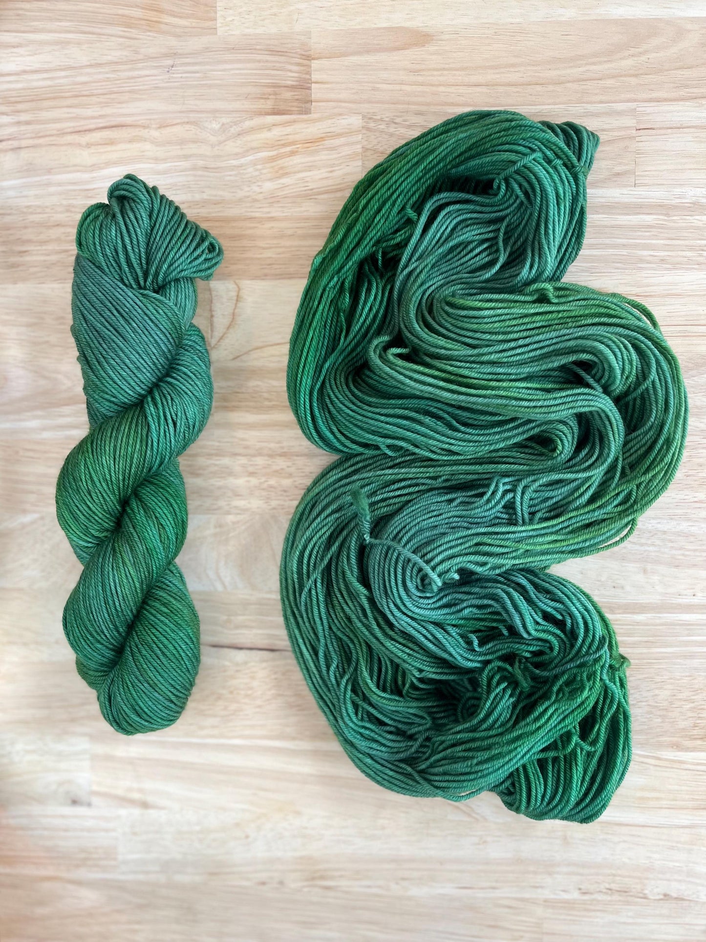 Skeins of DK weight hand dyed variegated jade green wool yarn.