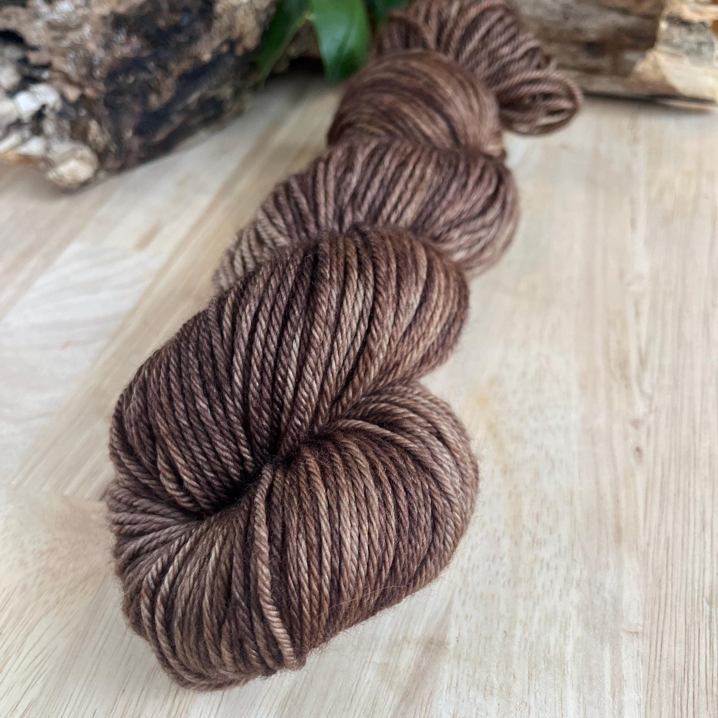 Hand dyed variegated neutral brown wool yarn arranged on a wooden backdrop.