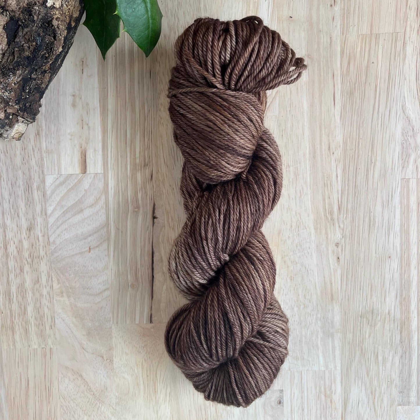 Hand dyed variegated neutral brown wool yarn arranged on a wooden backdrop.