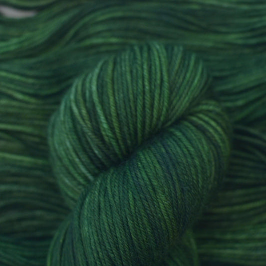 Skein of hand dyed variegated green merino yarn.