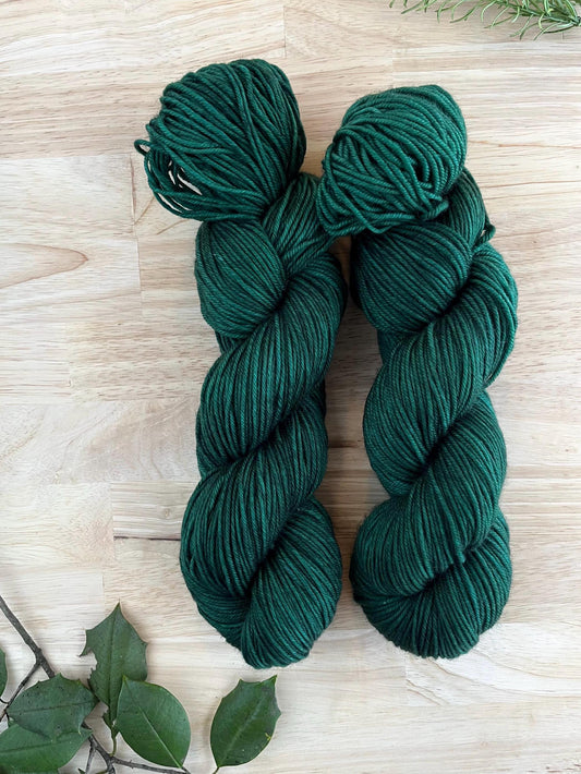 Skeins of hand dyed dark forest green merino wool yarn.