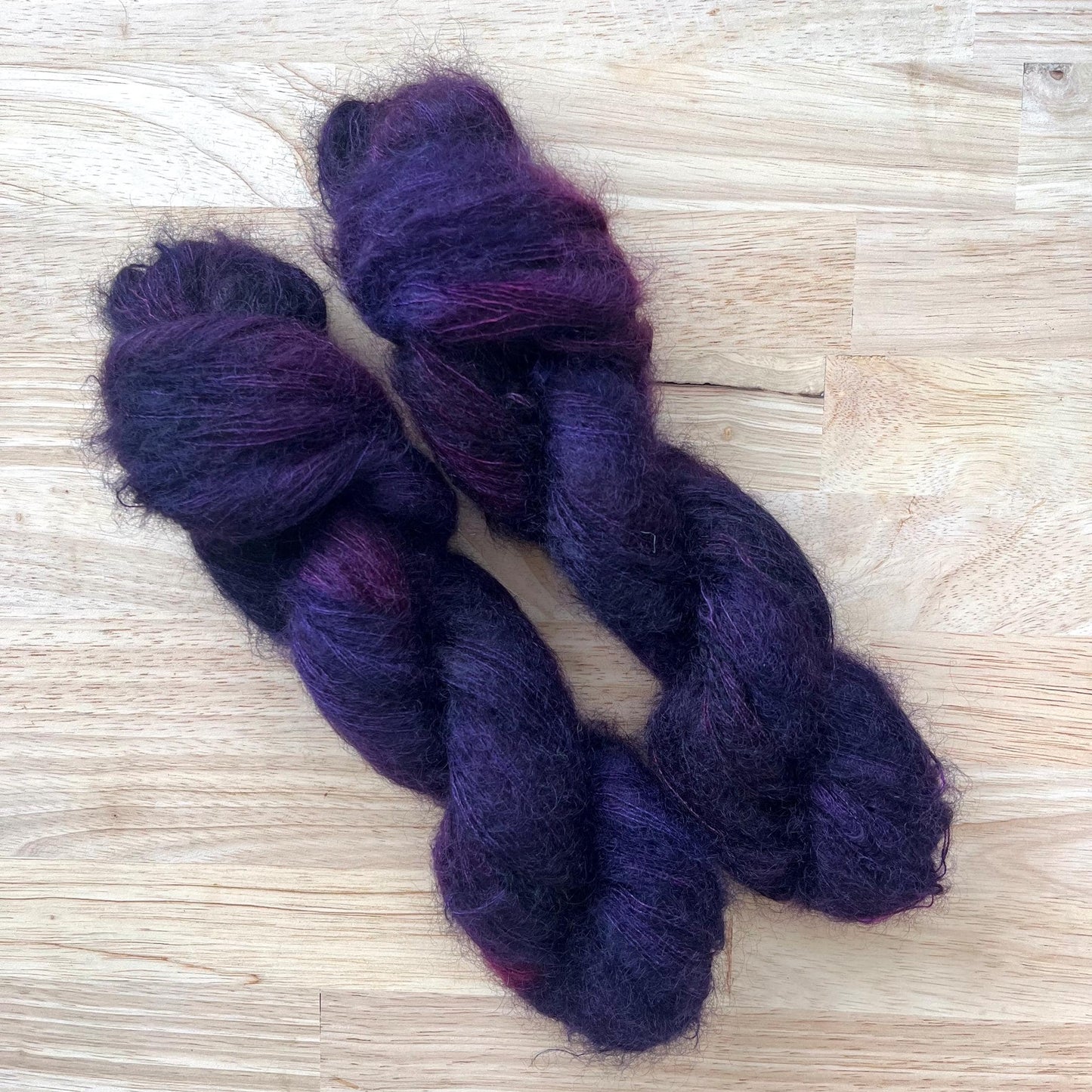 Skeins of dark purple variegated mohair lace weight yarn.