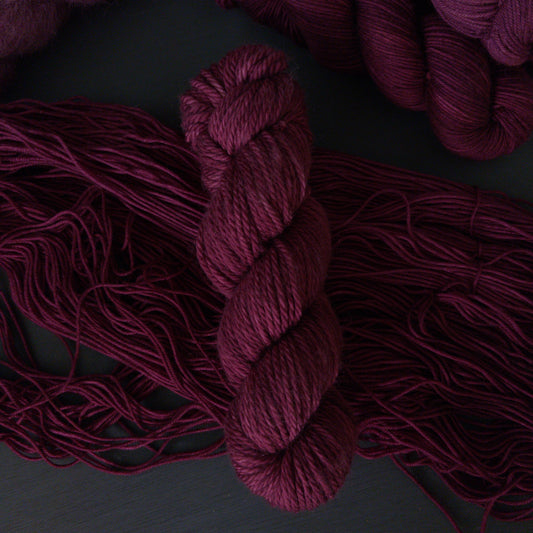Burgundy yarn skeins on a dark background