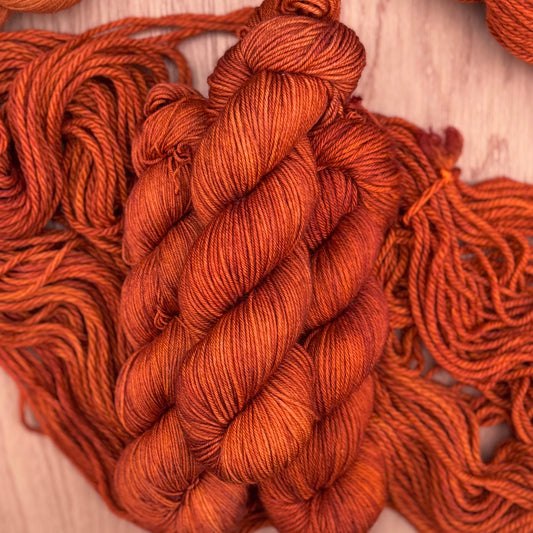 Close-up of orange yarn skeins on a wooden surface