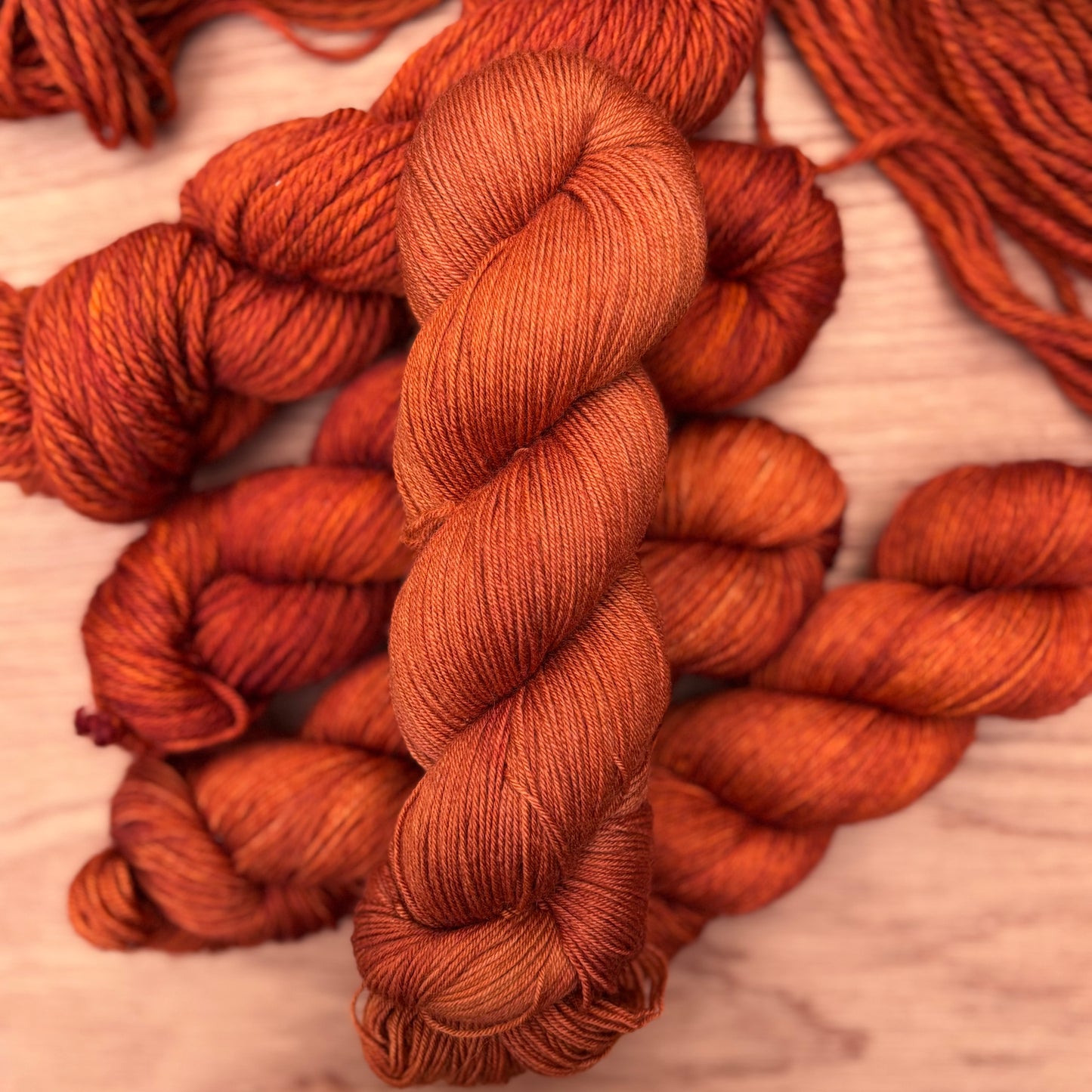 Close-up of orange wool yarn skeins on a wooden surface