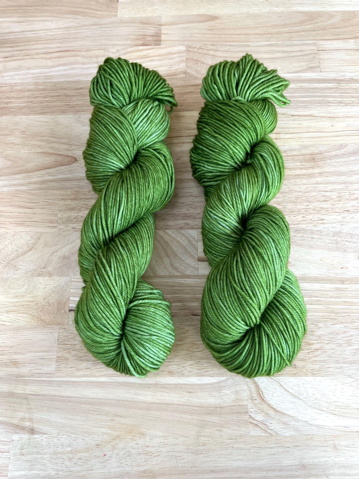 Skeins of hand dyed warm spring green merino wool yarn.