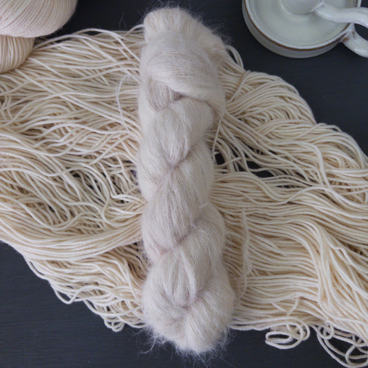 White skein of hand dyed alpaca yarn on a dark surface