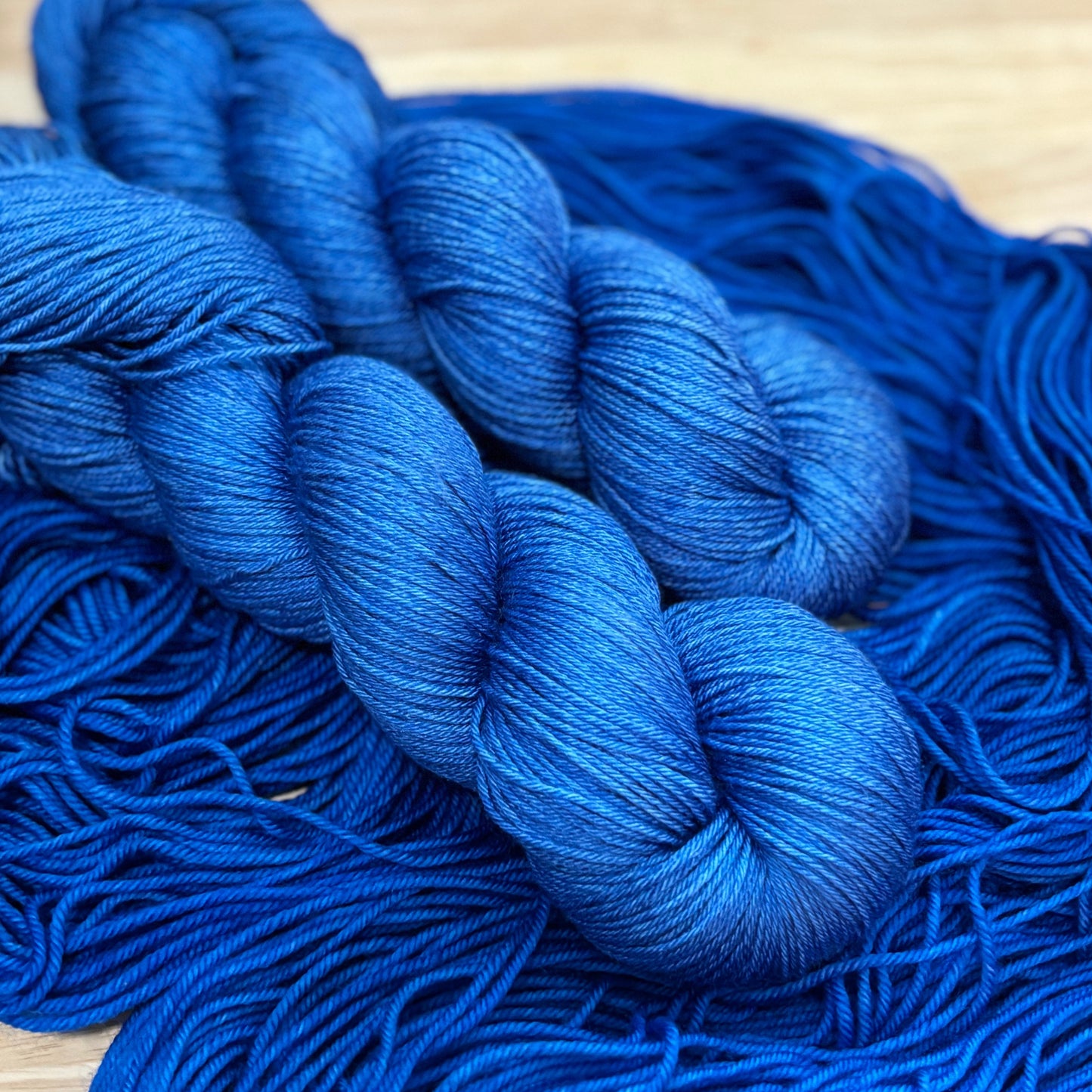 Hand dyed blue silk yarn skeins on a wooden surface
