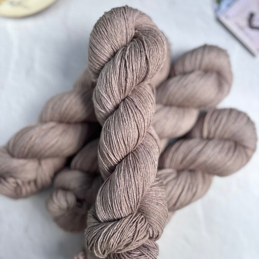 Skeins of beige hand dyed yarn on a light surface