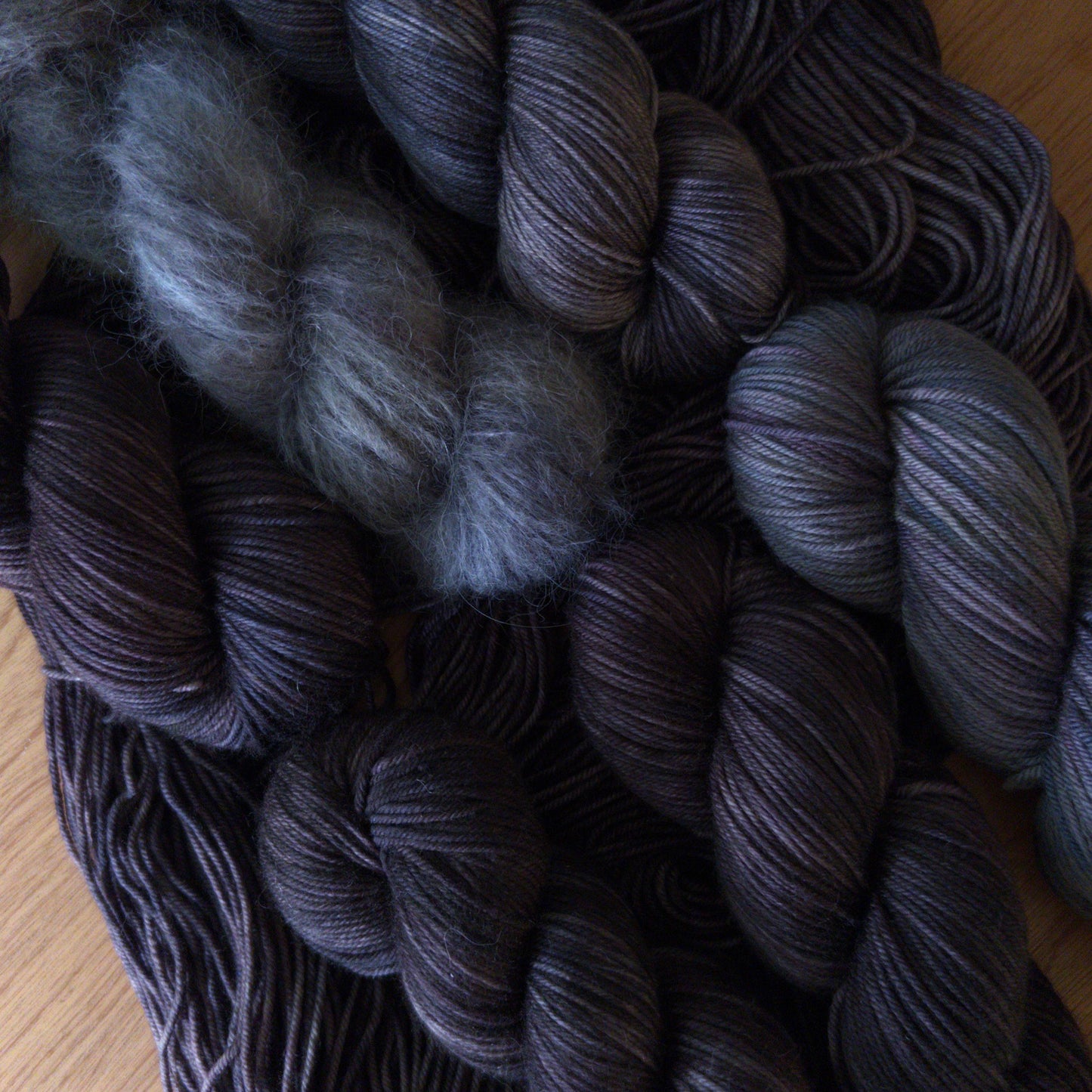Bundles of dark gray yarn on a wooden surface