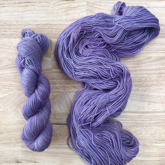 Skeins of muted purple yarn against a wood background.