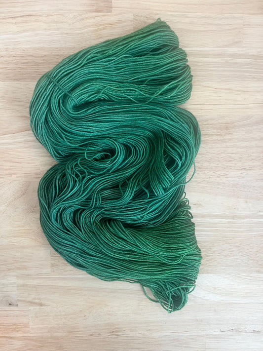 A knit swatch of hand dyed variegated jade green merino and silk yarn.