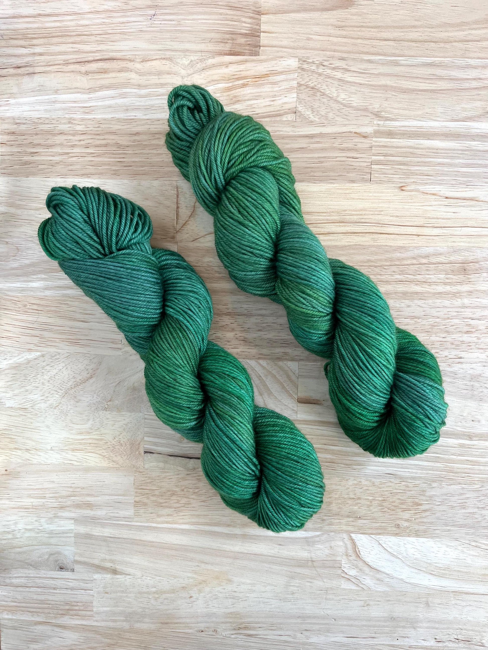 Skeins of sock weight hand dyed variegated jade green wool yarn.