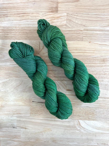 Skeins of sock weight hand dyed variegated jade green wool yarn.