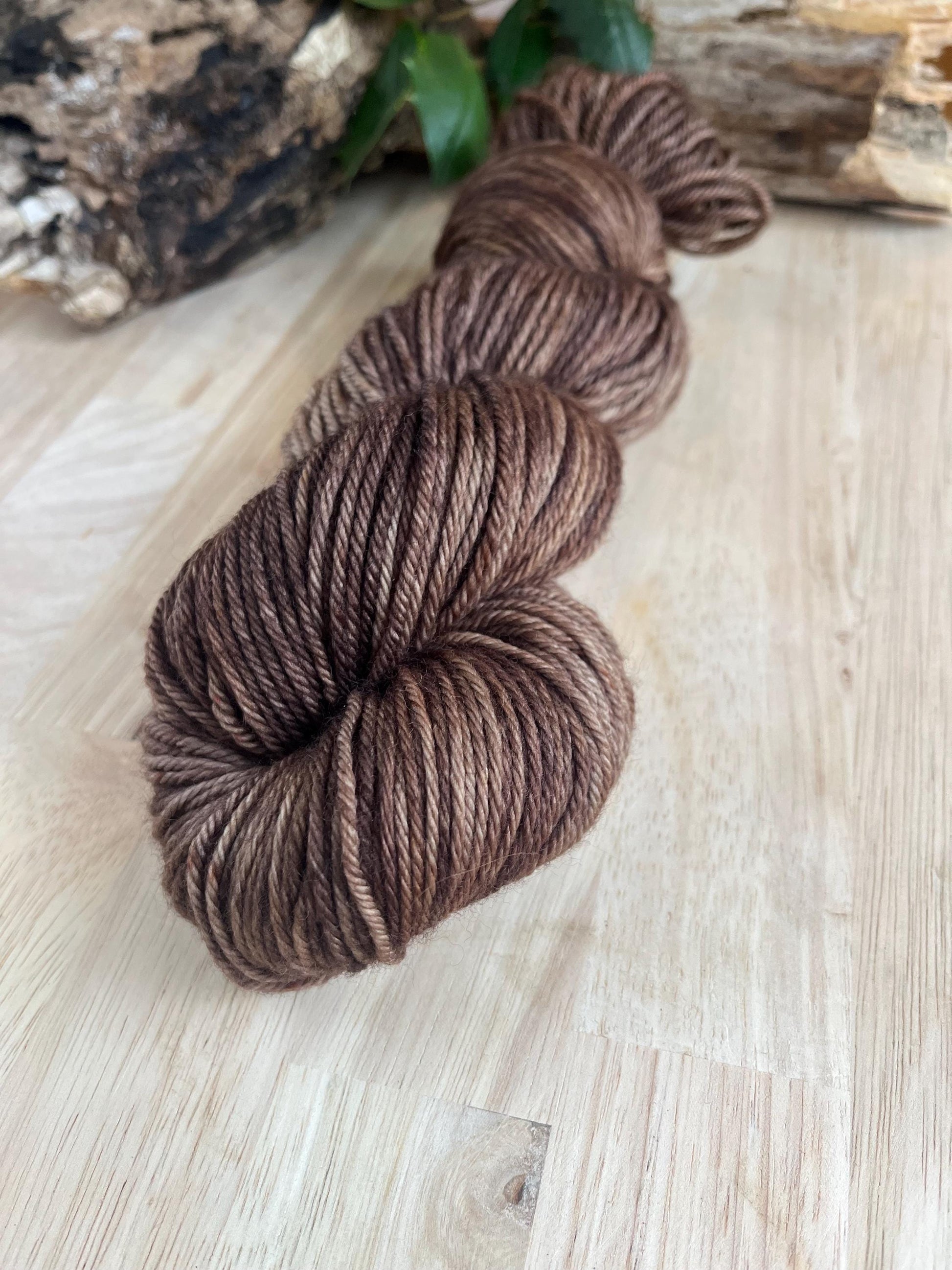 Hand dyed variegated neutral brown wool yarn arranged on a wooden backdrop.