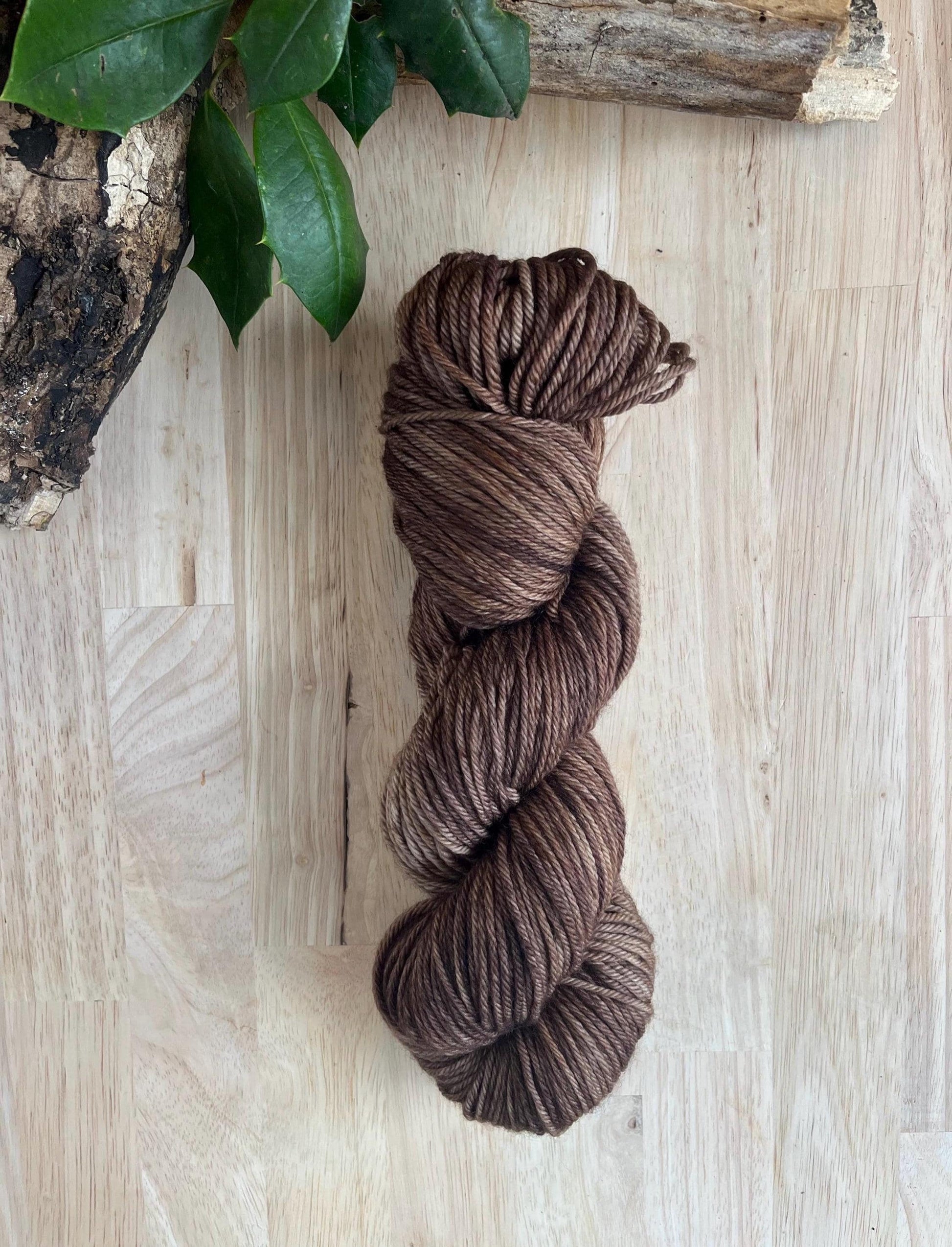 Hand dyed variegated neutral brown wool yarn arranged on a wooden backdrop.