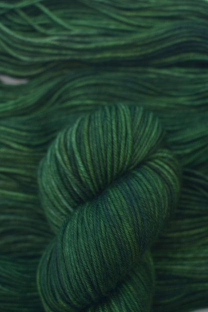 Skein of hand dyed variegated green merino yarn.