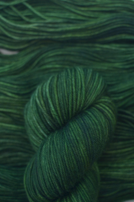 Skein of hand dyed variegated green merino yarn.