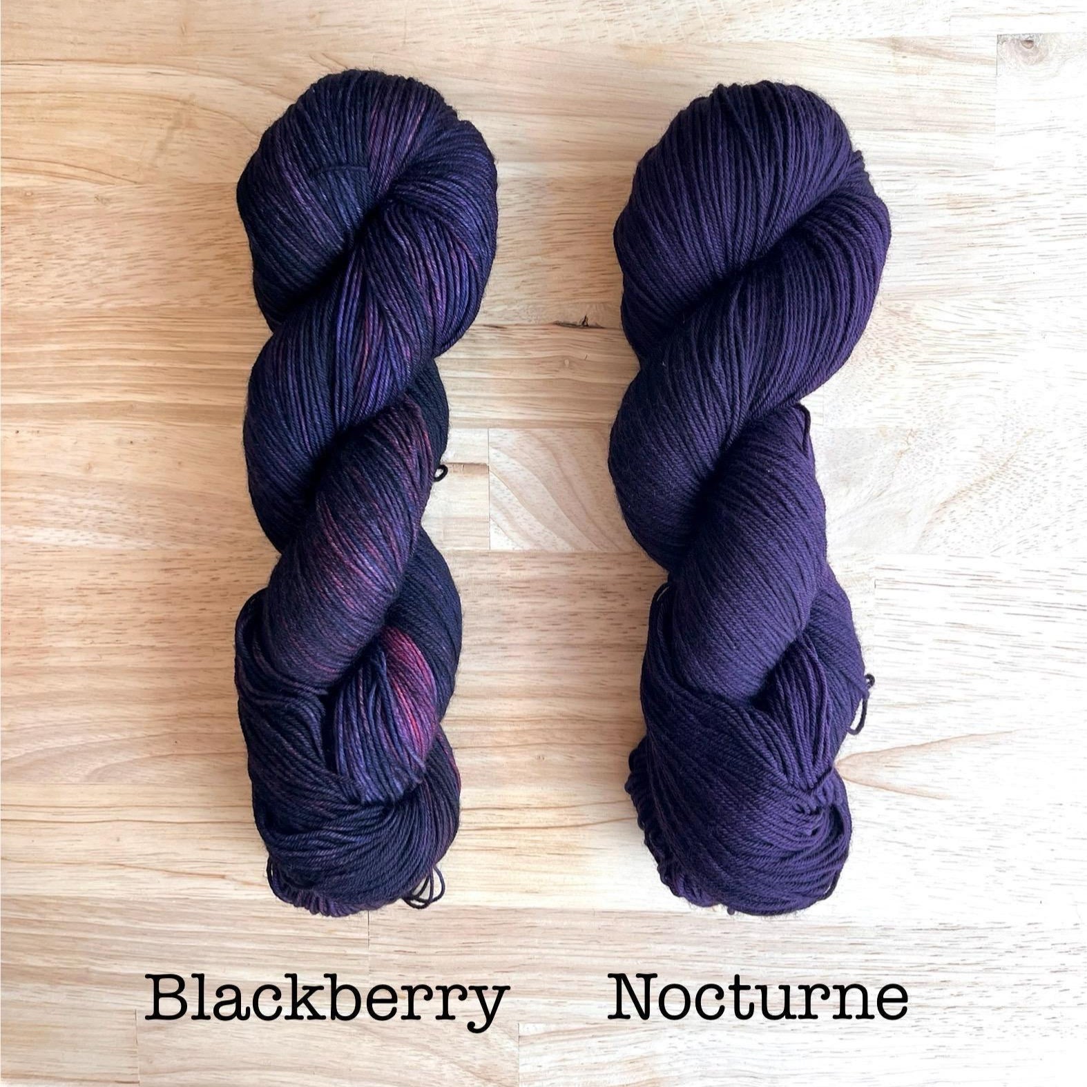 Skeins of hand dyed wool yarn in variegated dark purple and solid dark purple
