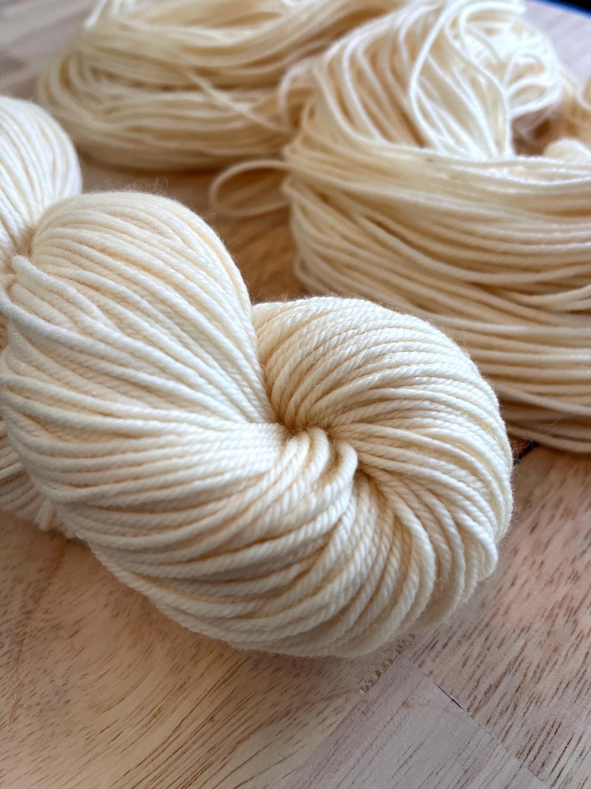 Skeins of creamy off white hand dyed merino wool yarn.