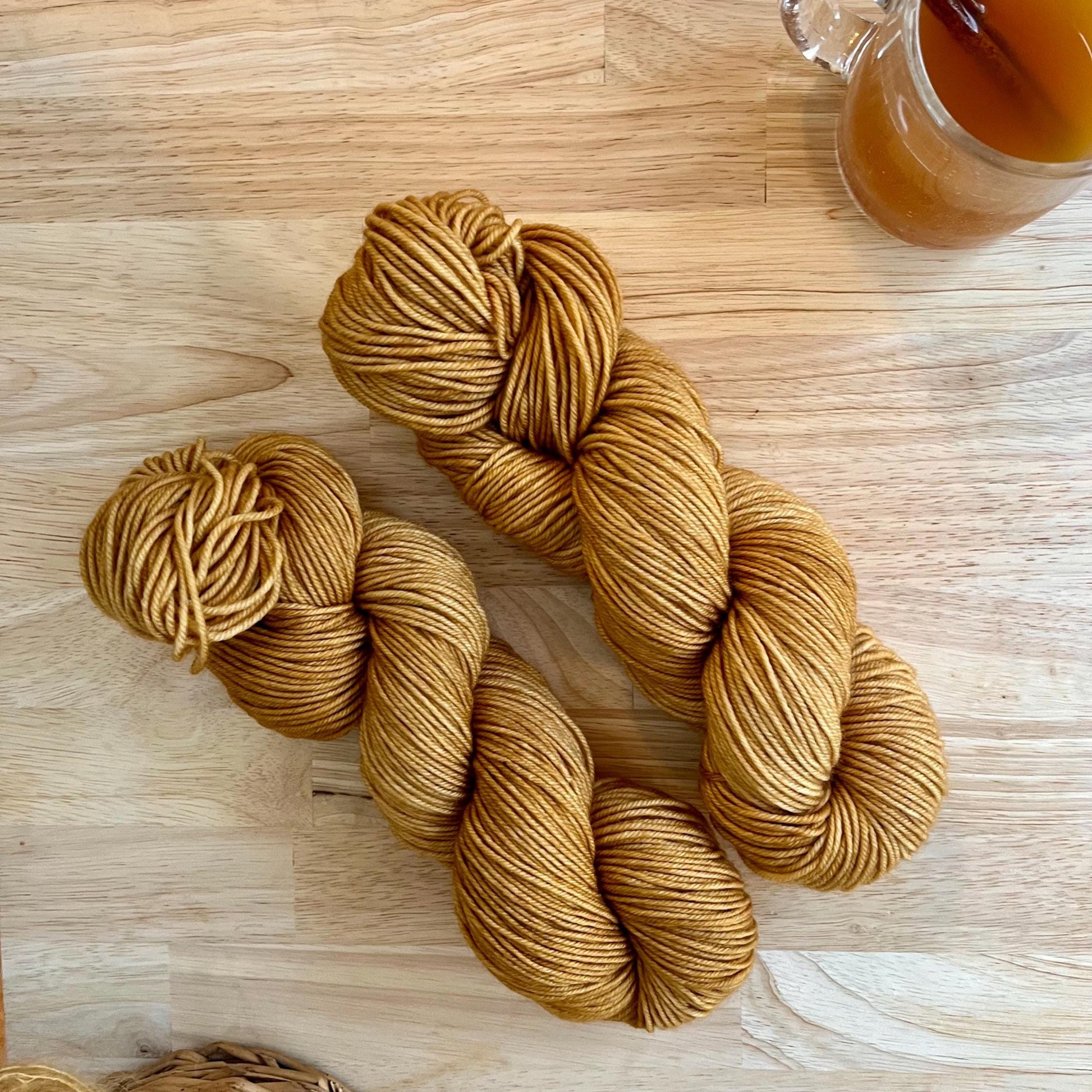Skeins of hand dyed camel yarn on a wood backdrop.