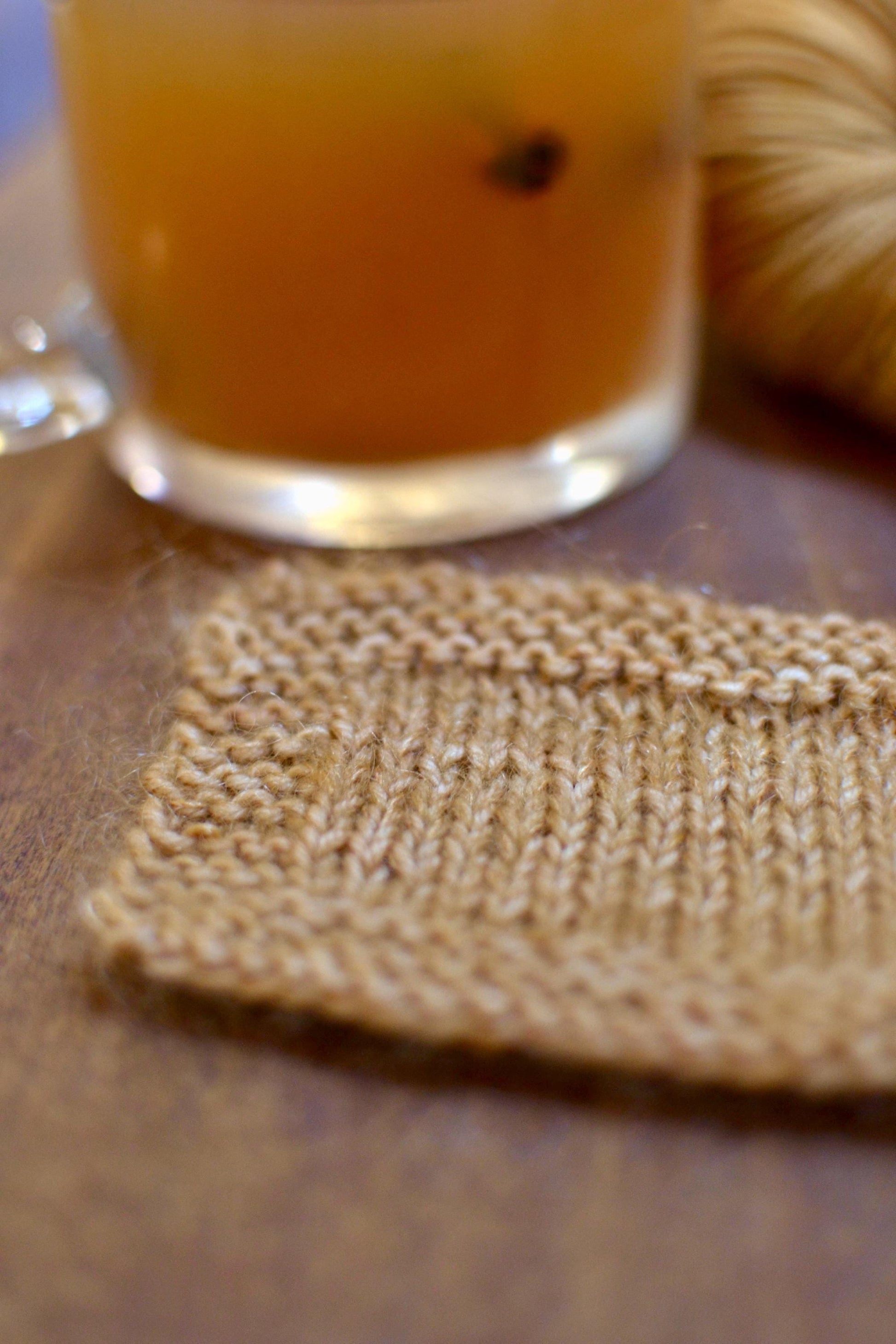 A knit swatch of warm tan hand dyed yarn, made of sock weight and lace weight mohair yarn knit together.