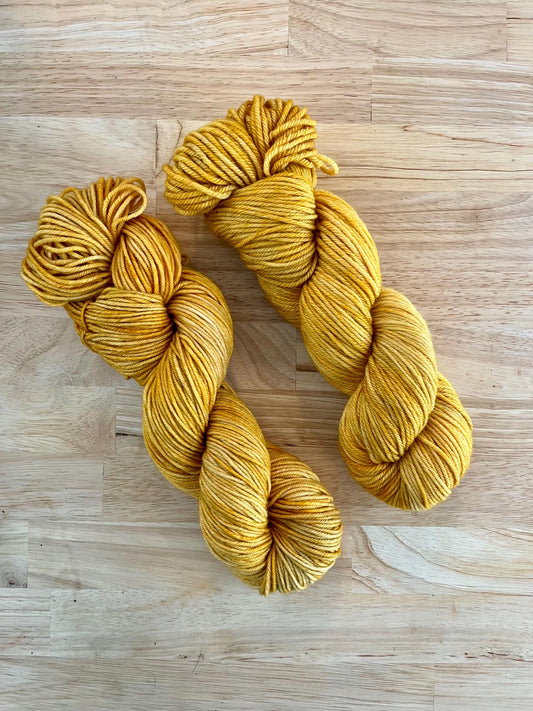 Two skeins of hand dyed variegated yellow wool yarn.