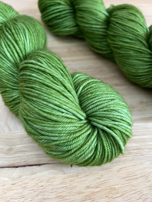 Skeins of hand dyed warm spring green merino wool yarn.