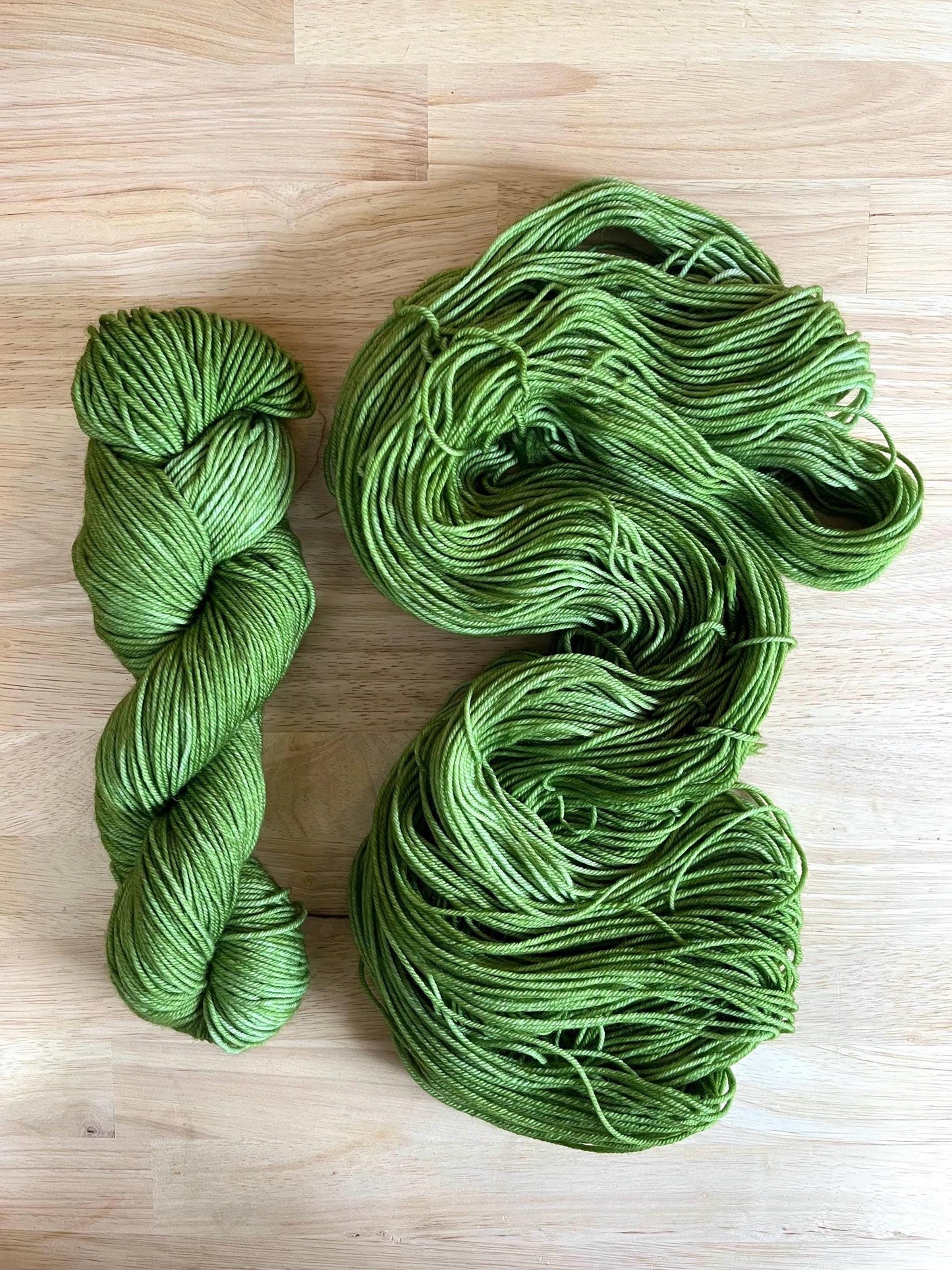 Skeins of hand dyed warm spring green merino wool yarn.