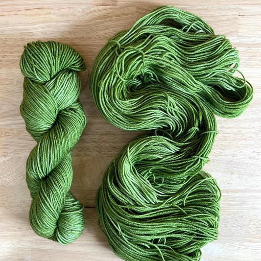 Skeins of hand dyed warm spring green merino wool yarn.