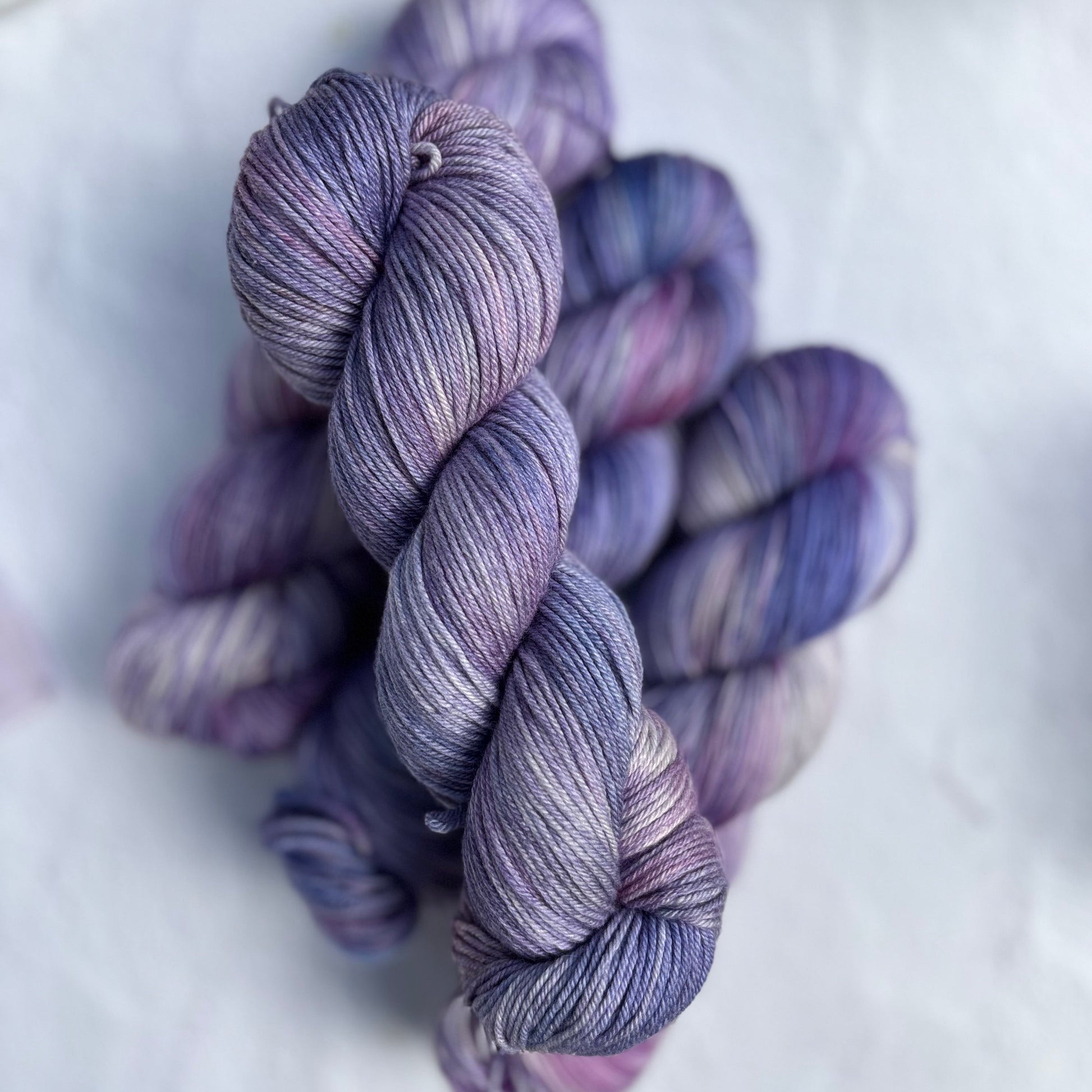 Purple and blue skeins of yarn on a white surface