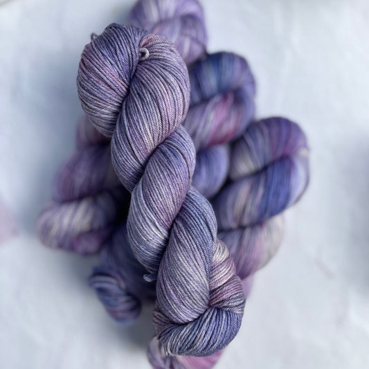 Purple and blue skeins of yarn on a white surface