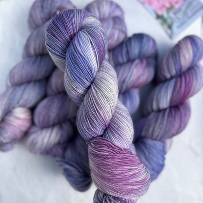 Bundles of purple and blue yarn on a white surface