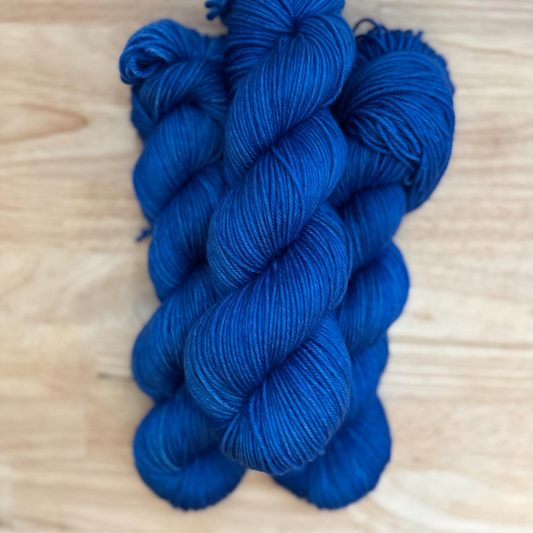 Two skeins of blue yarn on a wooden surface