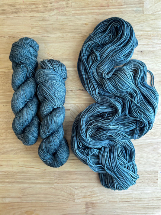 Two skeins of blue hand dyed yarn on a wooden surface