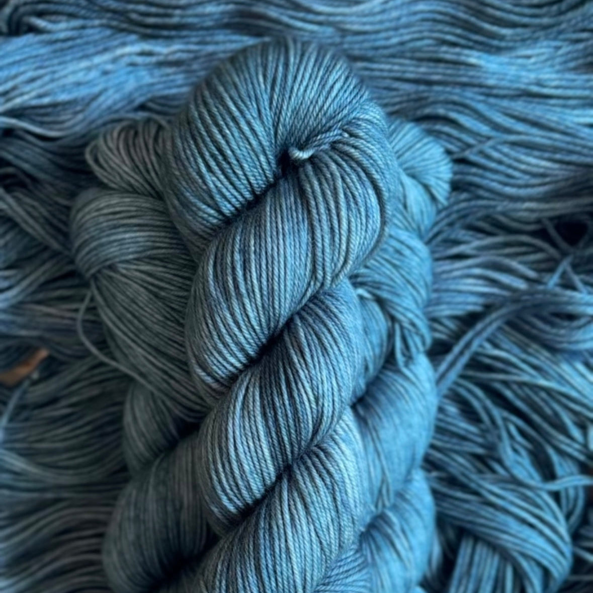 Blue skein of hand dyed yarn on a textured blue background