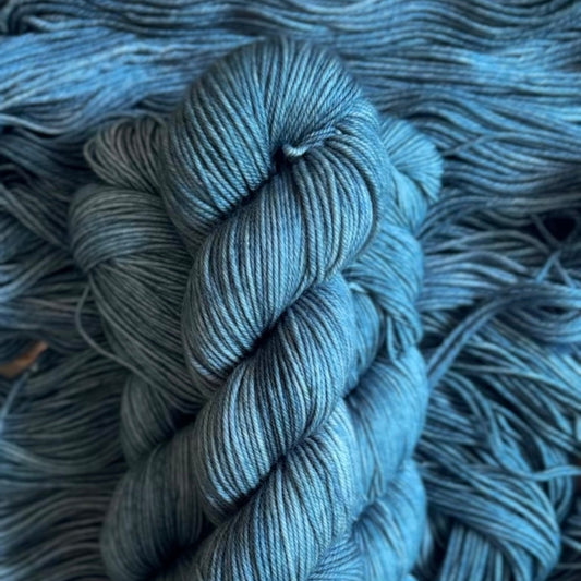 Blue skein of hand dyed yarn on a textured blue background