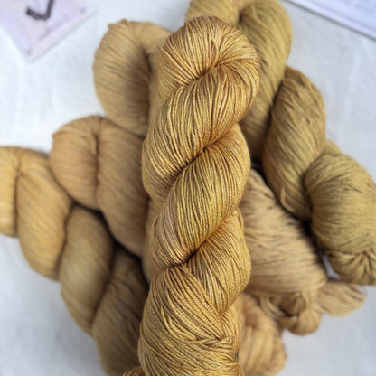 Three skeins of gold yarn on a white surface