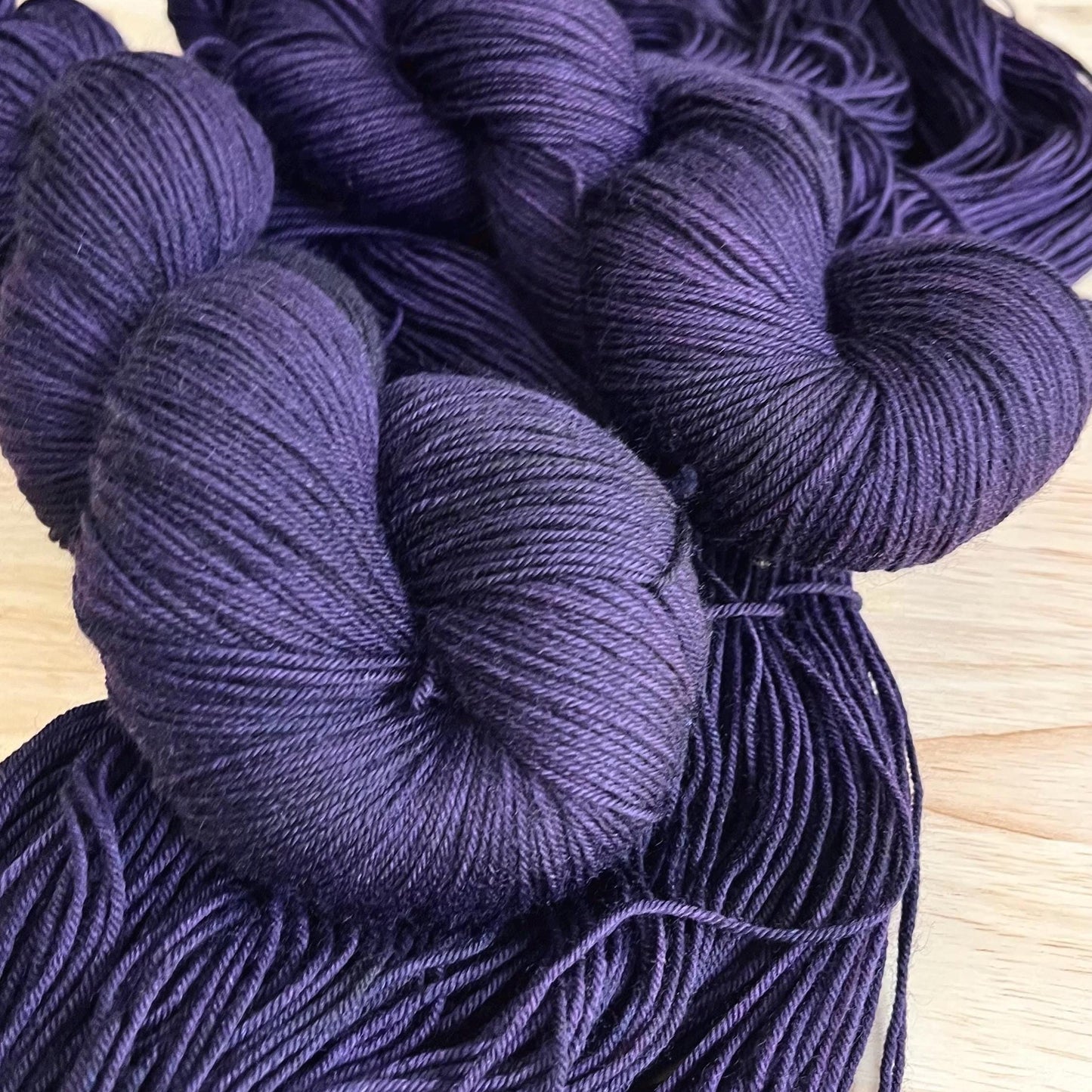 Skeins of hand dyed dark purple merino wool yarn 