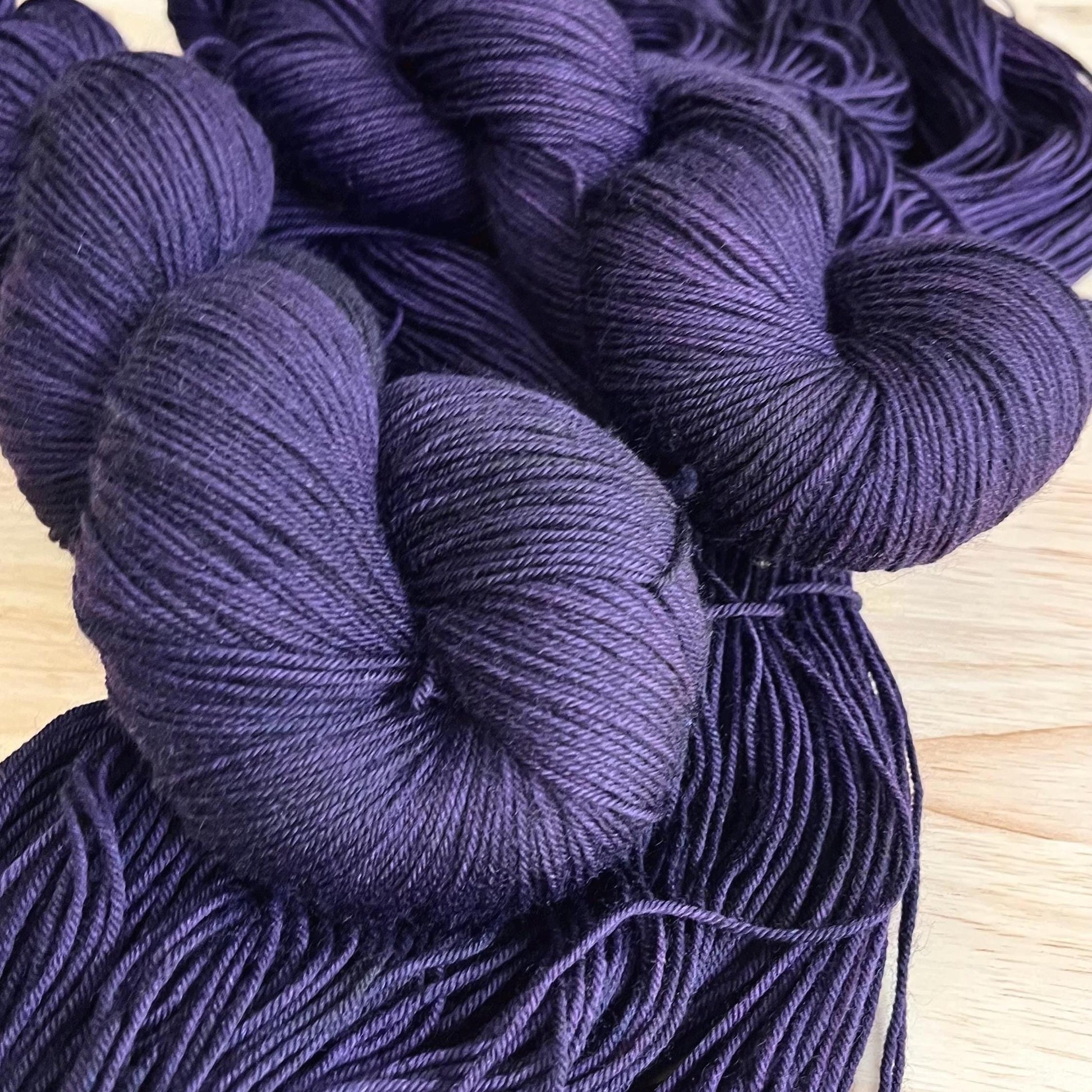 Skeins of hand dyed dark purple merino wool yarn 