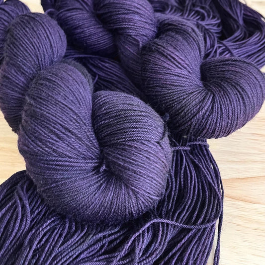 Skeins of hand dyed dark purple merino wool yarn 