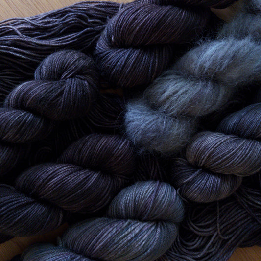 Hanks of dark gray yarn on a wooden surface