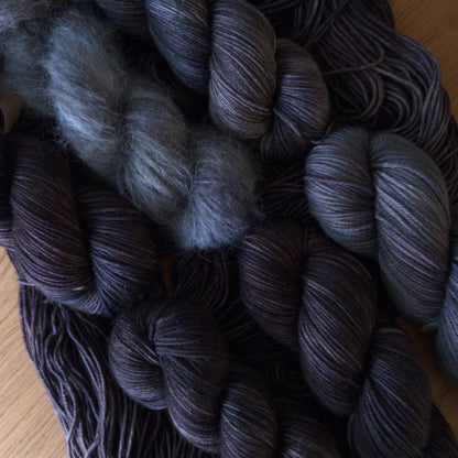 Bundles of dark gray yarn on a wooden surface