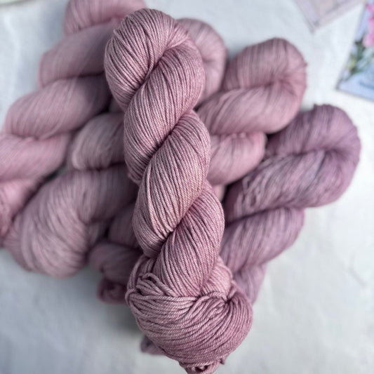 Pink skeins of yarn on a light surface with blurred background