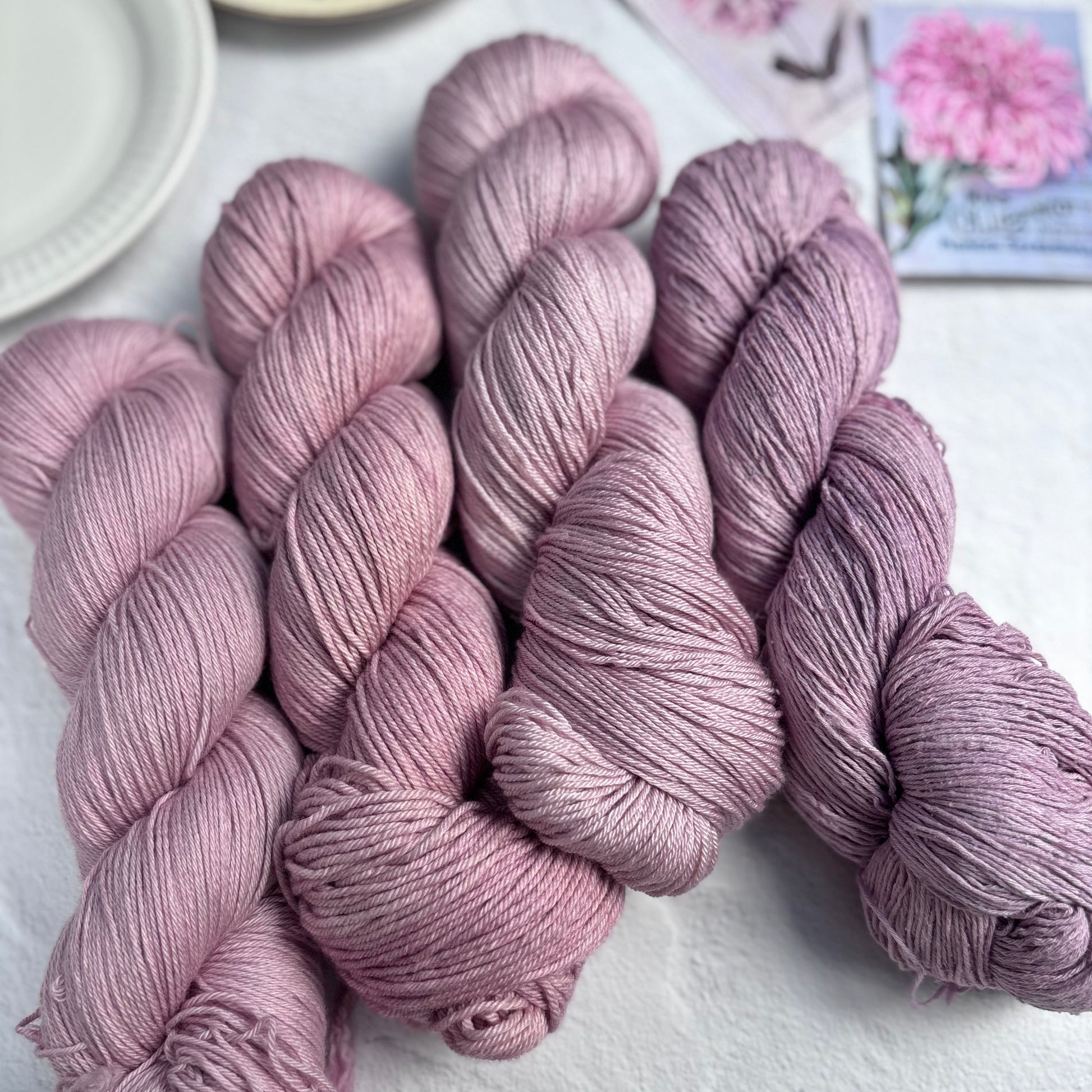 Three skeins of pink yarn on a white surface with a blurred background