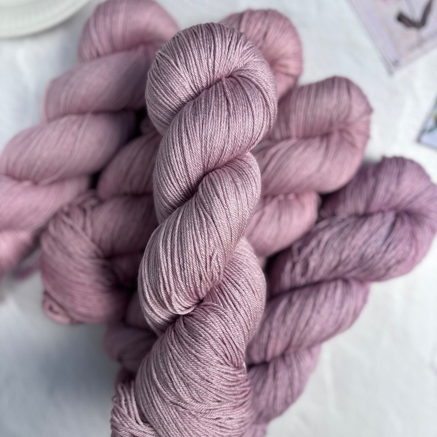 Pink yarn skeins on a light surface with a blurred background