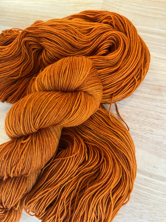 Warm rust orange hand dyed wool yarn arranged in a skein.