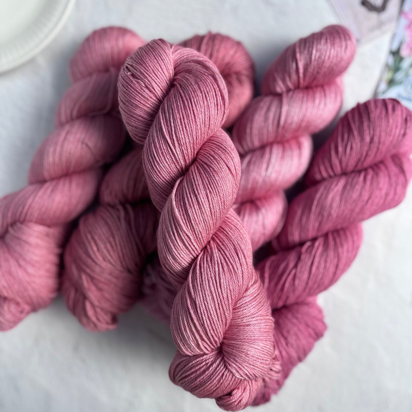 Pink yarn skeins on a light surface with a blurred background