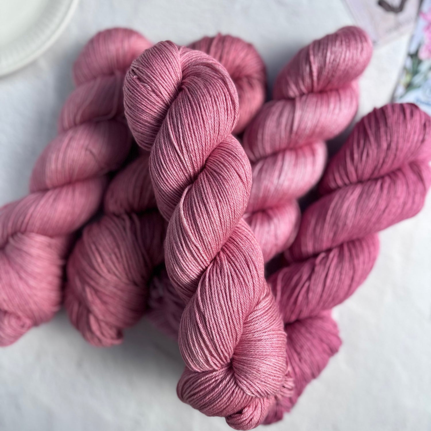 Pink yarn skeins on a light surface with a blurred background